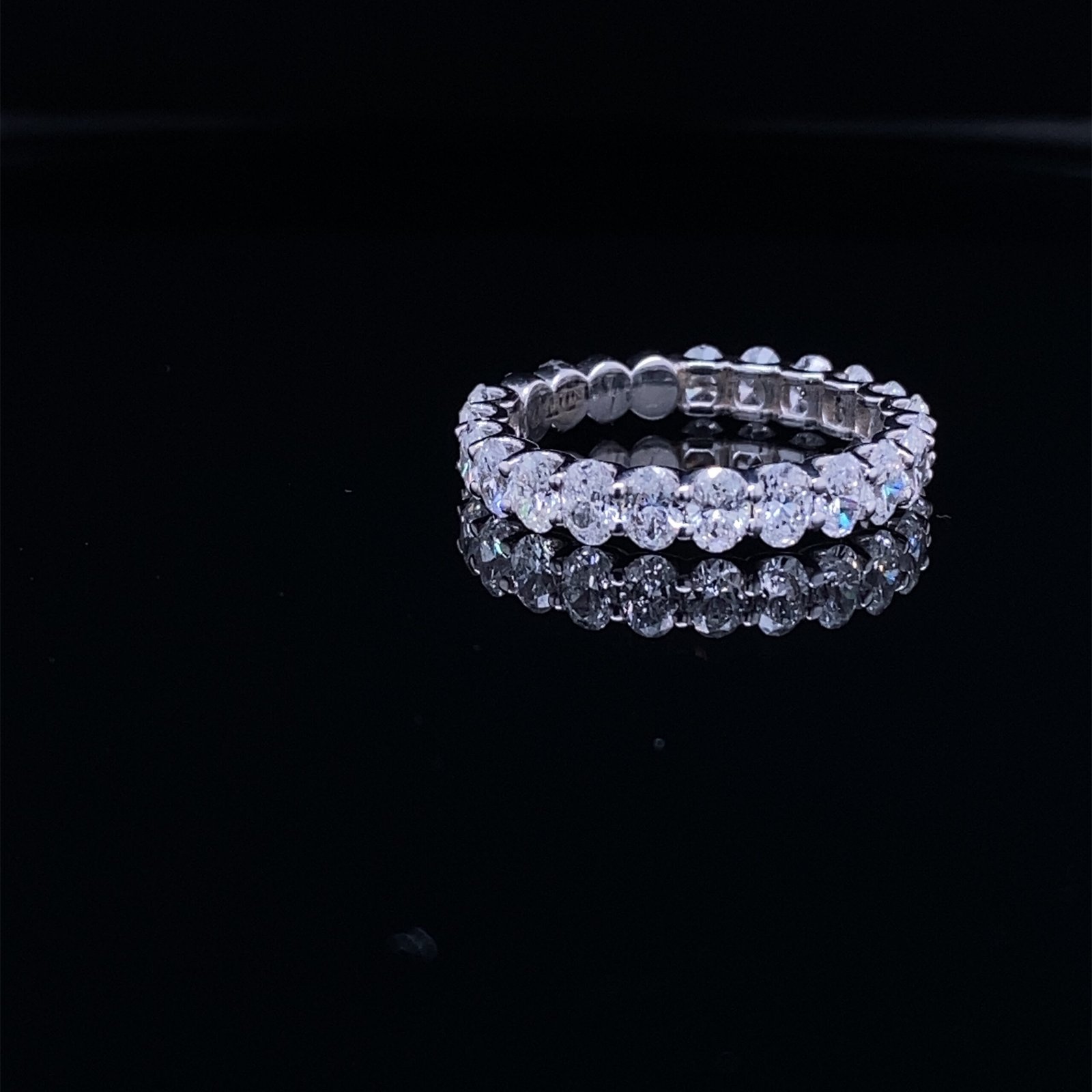 Diamond eternity ring reflecting on black surface
